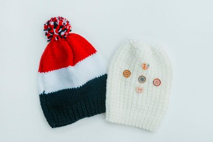 Choose from a yellow patterned beanie with button adornments or a colourful red, white and blue striped beanie with a pompom