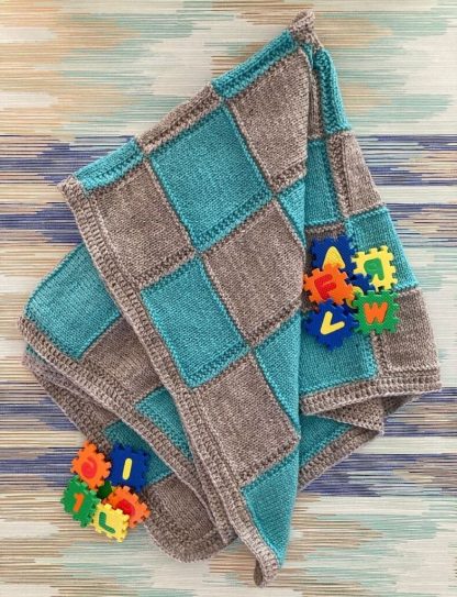 Hand knitted blue and grey patterned squares baby's blanket