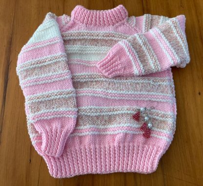 Hand knitted chunky jumper in pink and white Round neck Long sleeves Ribbing around neckline, cuffs and hem 100% Acrylic yarn Completed garment measurements: Chest all around: 78cm Length, shoulder to hem ribbing: 46cm Sleeve seam length: 32cm