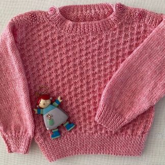 Stunning pink jumper hand knitted in the softest baby yarn, with an eye-catching pattern and with delightful polka dot buttons on both shoulders