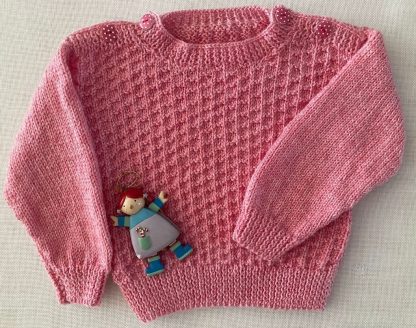 Stunning pink jumper hand knitted in the softest baby yarn, with an eye-catching pattern and with delightful polka dot buttons on both shoulders