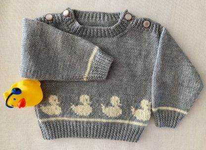 Hand knitted jumper in grey yarn with a row of ducklings featured front and back Buttons on both shoulders