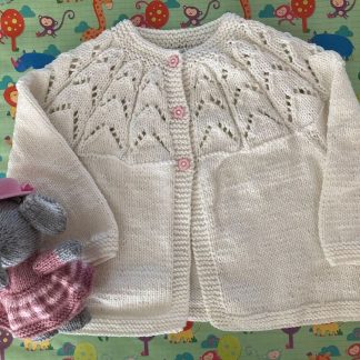 Hand knitted round neck matinee jacket in white with a beautiful lacy yoke 3 pink daisy buttons in front