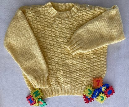 Hand knitted yellow jumper with a distinctive pattern Round neck Buttons on one shoulder Long sleeves Ribbing around neckline, cuffs and hem