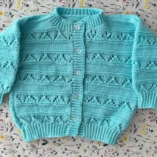 Hand knitted beautiful turquoise cardigan with lacy panels 5 buttons down the front Round neck Long sleeves Ribbing around neckline, cuffs and hem 100% Acrylic yarn Completed garment measurement: Chest all around: 66cm Length, shoulder to hem ribbing: 29cm Sleeve seam length: 21cm