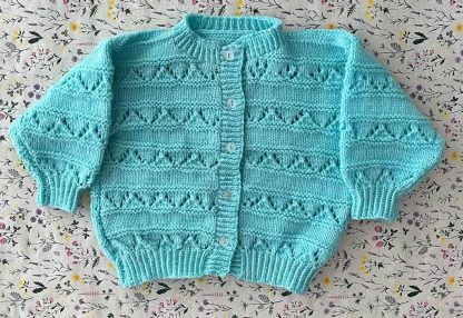 Hand knitted beautiful turquoise cardigan with lacy panels 5 buttons down the front Round neck Long sleeves Ribbing around neckline, cuffs and hem 100% Acrylic yarn Completed garment measurement: Chest all around: 66cm Length, shoulder to hem ribbing: 29cm Sleeve seam length: 21cm