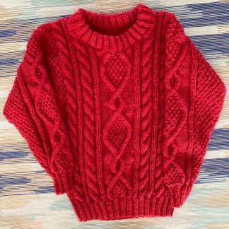 Hand knitted stunning red jumper knitted in Aran style Round neck Long sleeves Ribbing around neckline, cuffs and hem 100% Acrylic yarn Completed garment measurements Chest all around: 66cm Length, shoulder to hem ribbing: 39cm Sleeve seam length: 32cm For ages 2-3 years